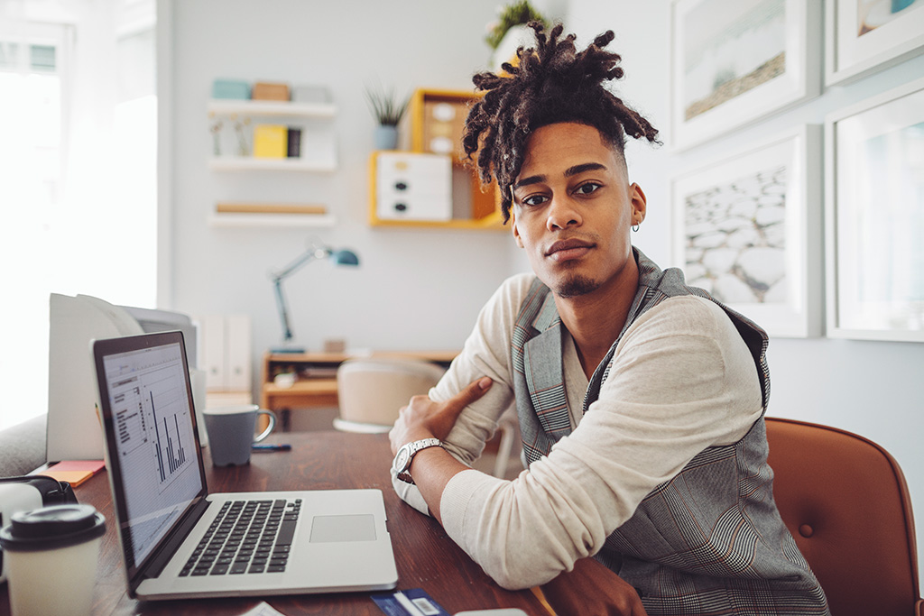 man sitting in front of a desk and laptop